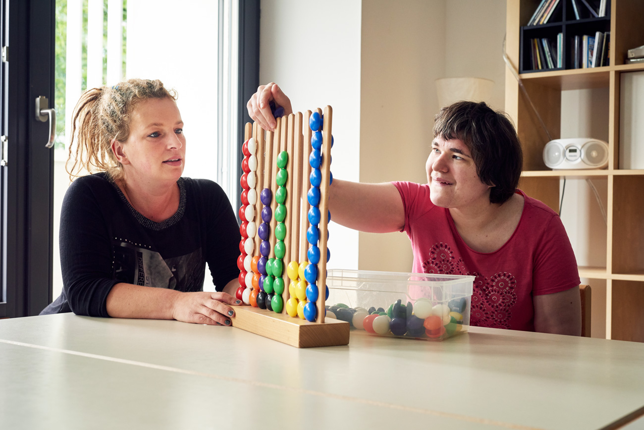 FSJlerin spielt ein Spiel mit einer Bewohnerin der LebensWerkstatt