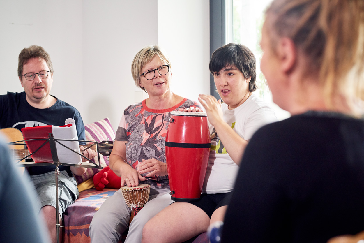 Zwei Frauen trommeln und ein Mann spielt Gitarre.