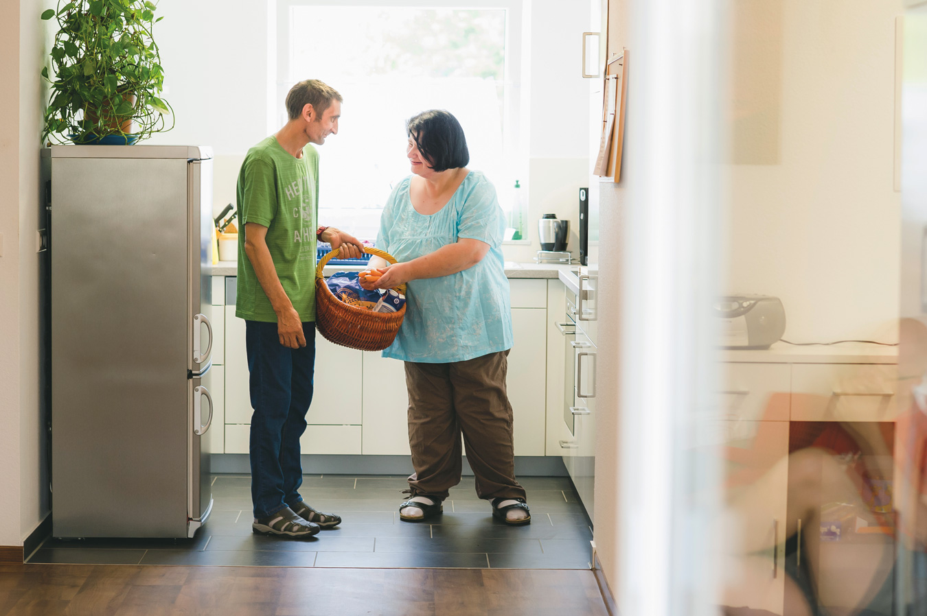 In einer Küche des begleitenden Wohnens hilft eine Frau einem Bewohner mit den Einkäufen.