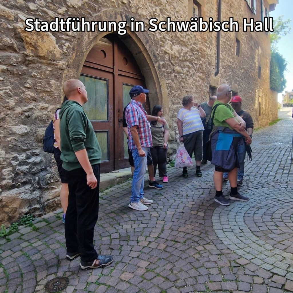 Gruppe von Menschen auf Stadtführung vor einem alten Gebäude in Schwäbisch Hall. Kopfsteinpflaster im Vordergrund.