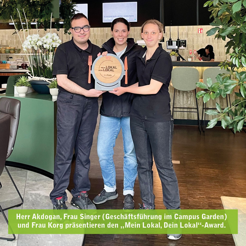 Drei Menschen präsentieren den Mein Lokal, Dein Lokal-Award in einem modernen Restaurantumfeld.