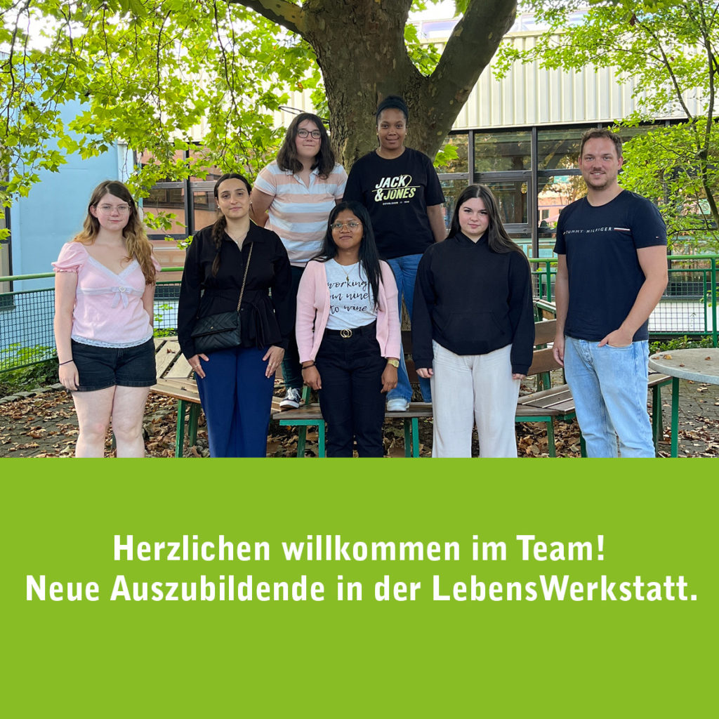 Gruppe neuer Auszubildender steht draußen vor einem Baum bei der LebensWerkstatt. Willkommen im Team.