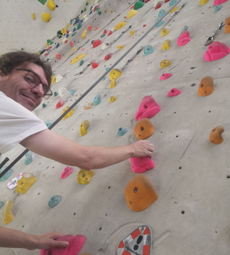 foto zeigt einen jungen mann an einer kletterwand