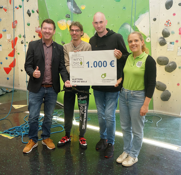 vier menschen halten einen grosßen scheck hoch