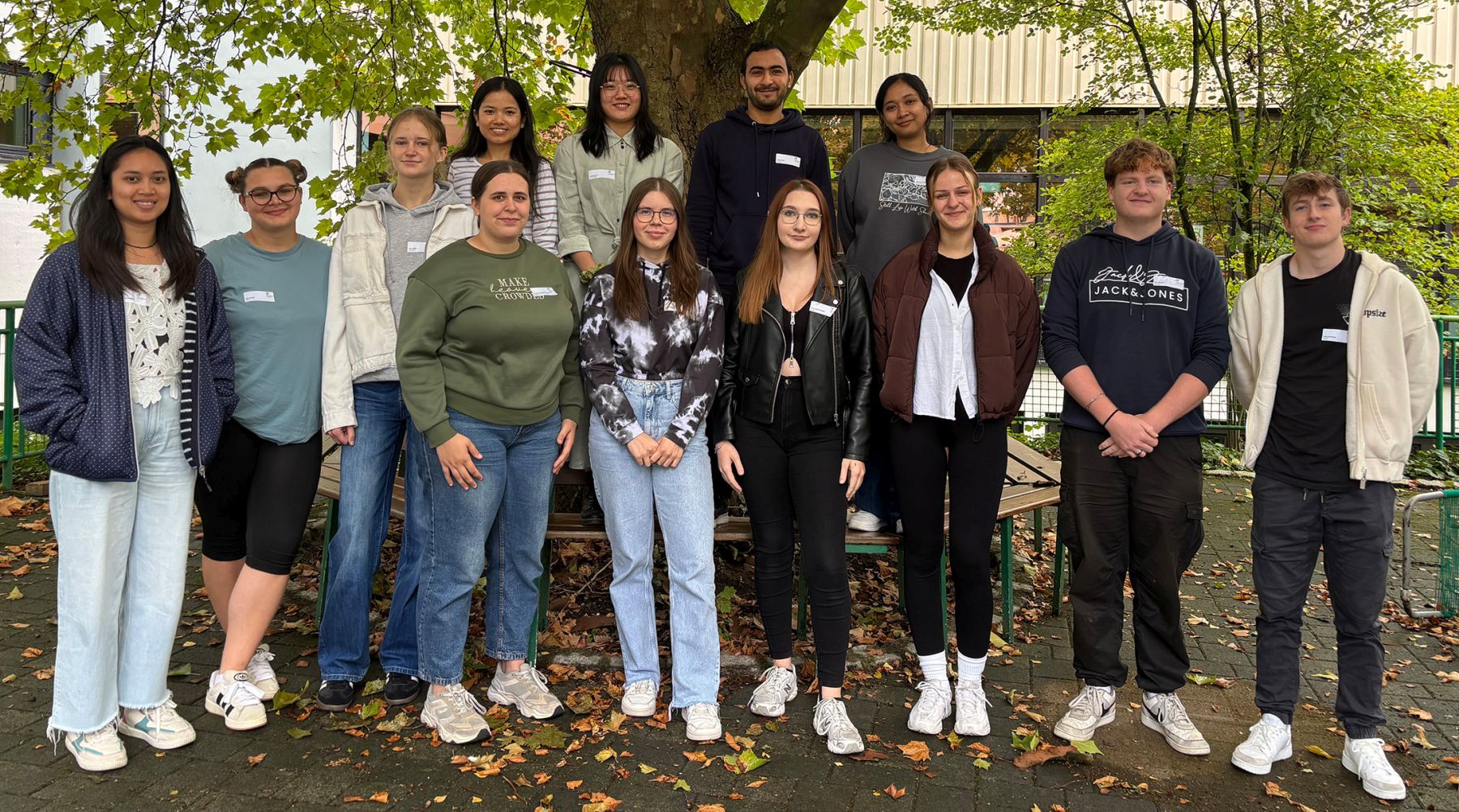 Eine Gruppe junger Menschen stehen unter einem Baum