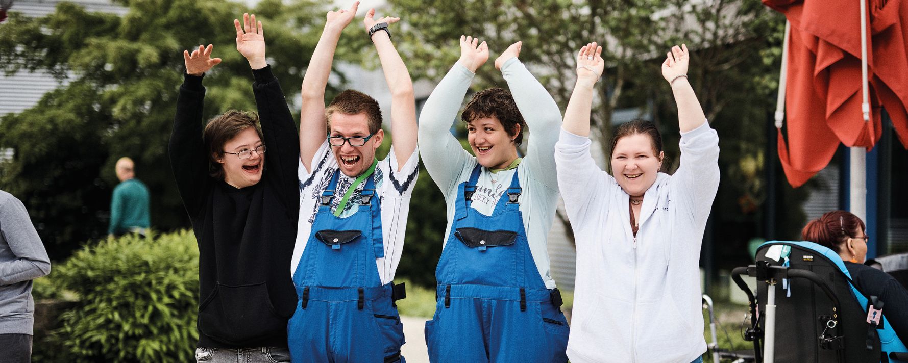 menschen halten sich im garten auf und vier leute heben beide arme hoch und lachen fröhlich