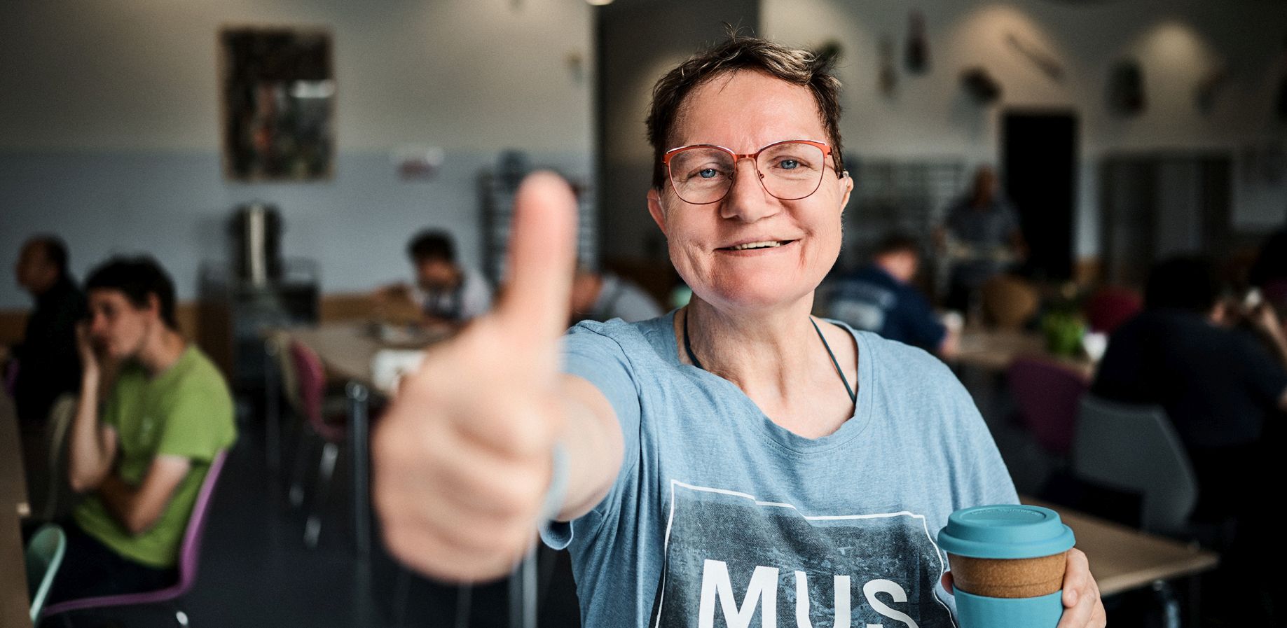 eine Frau lacht in die Kamera und hält den Daumen nach oben