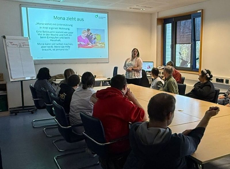 Eine Gruppe Menschen sitzt um einen großen Tisch bei einem Seminar