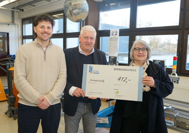 drei menschen halten einen großen scheck hoch