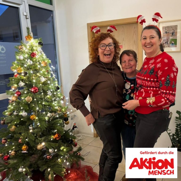 drei frauen stehen vor einem weihnachtsbaum und lachen