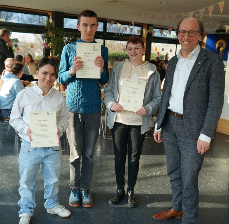 pfarrer manz steht neben drei menschen die zertifikate halten - alle lächeln