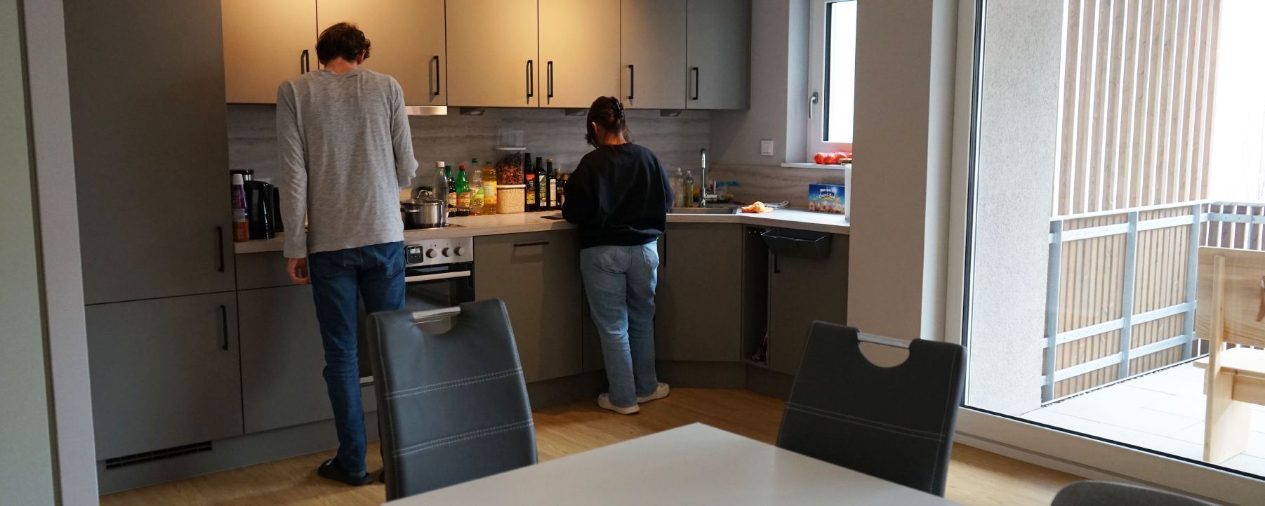 Zwei Personen stehen in einer modernen Küche und bereiten eine Mahlzeit vor.