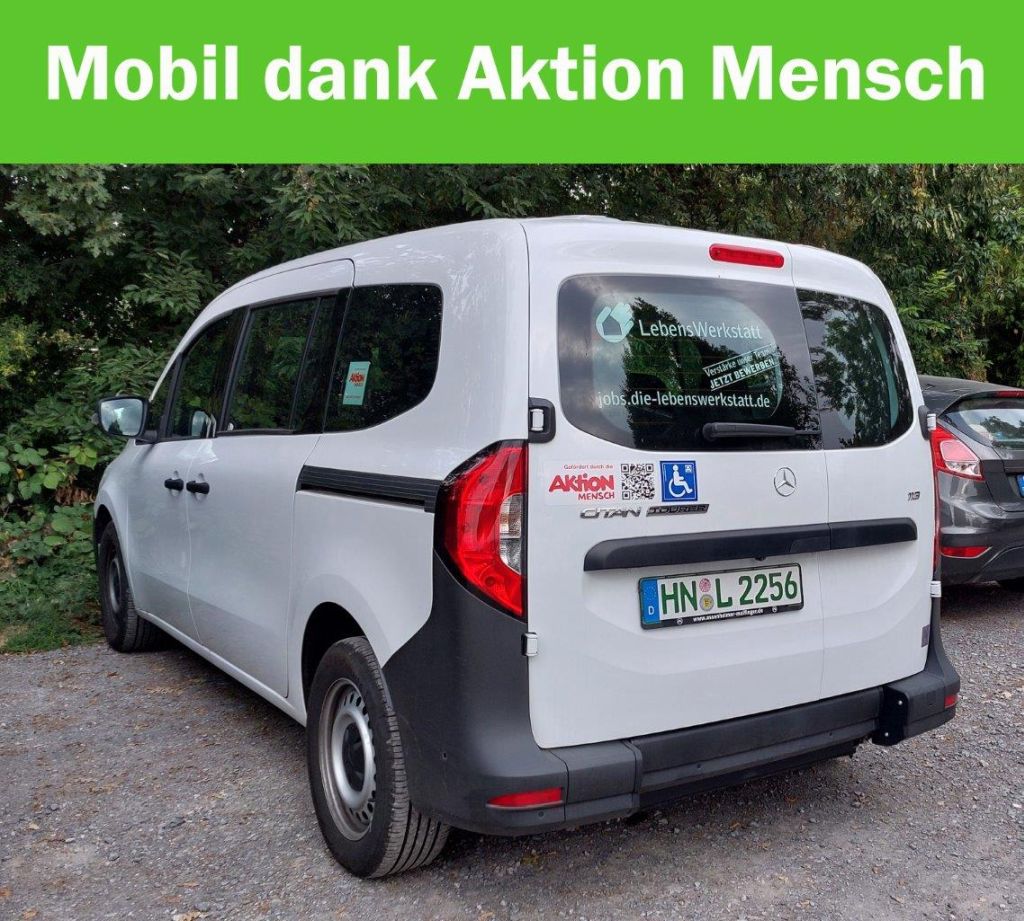 Ein weißer Van mit dem Logo von LebensWerkstatt steht unter Bäumen. Aufkleber zeigen die Aktion Mensch und barrierefreie Nutzung.