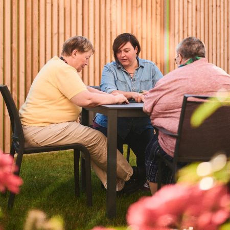 drei frauen sitzen an einem gartentisch
