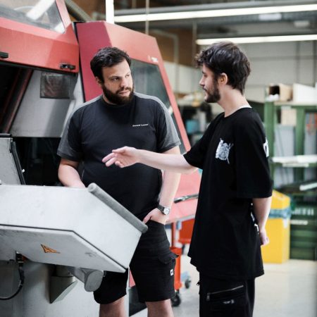 Ein Mann erklärt einem Mitarbeiter wie eine Maschine funktioniert